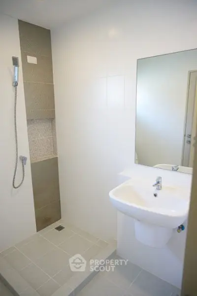 Modern minimalist bathroom with sleek shower and white sink.