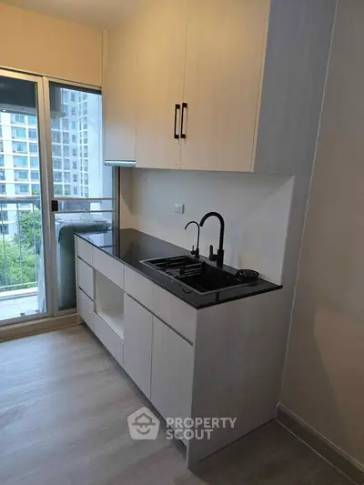Modern kitchen with sleek cabinetry and balcony view in urban apartment