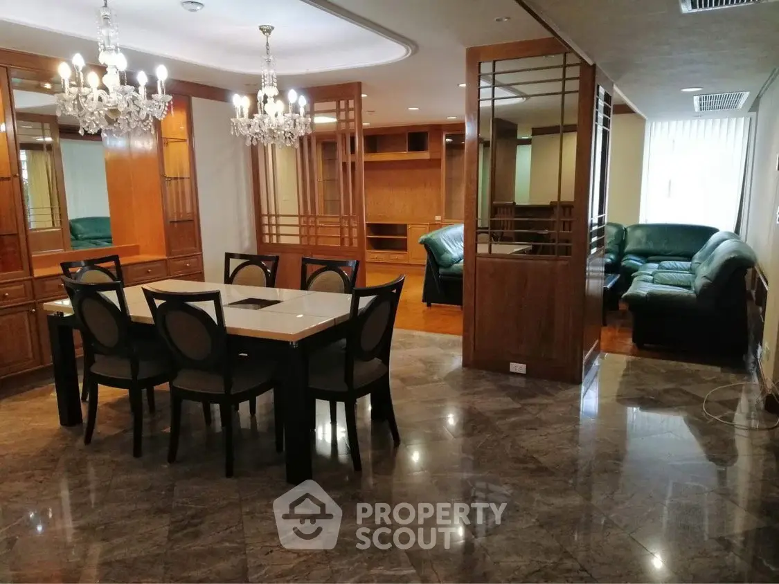 Luxurious open living and dining area with elegant chandeliers and marble flooring.