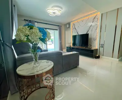 Luxurious living room with modern decor, large TV, and elegant lighting in a stylish home.