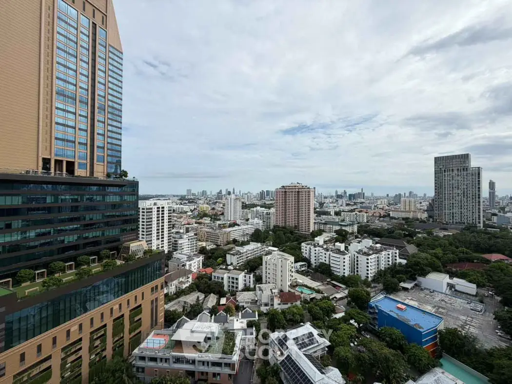 Stunning cityscape view from a high-rise building showcasing urban skyline and lush greenery.