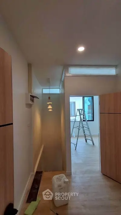 Modern interior hallway with wooden accents and ladder, showcasing renovation potential.