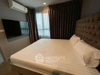 Modern bedroom with large bed, wall-mounted TV, and elegant curtains.