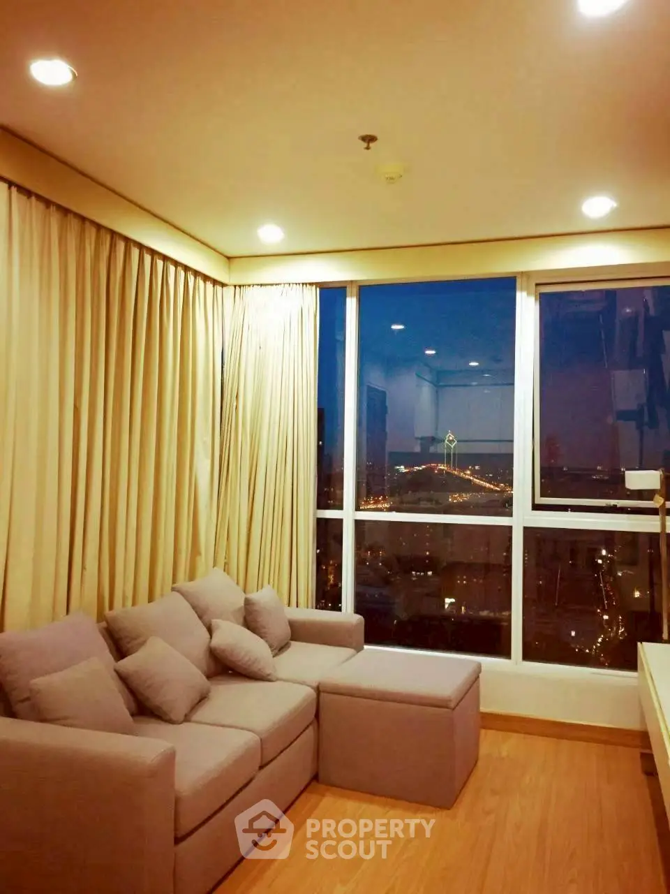 Cozy living room with city view, featuring a comfortable sofa and large windows.