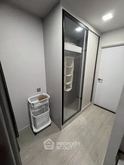 Modern storage room with sleek sliding door wardrobe and laundry basket