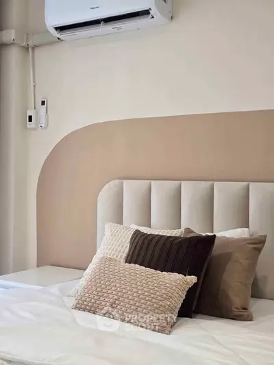 Modern bedroom with stylish headboard and cozy pillows under air conditioning unit.