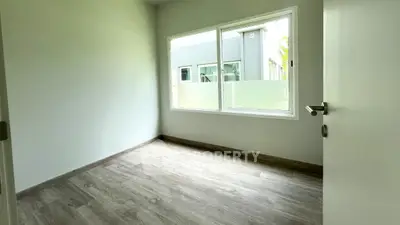 Bright empty room with large window and wooden flooring, ideal for customization.