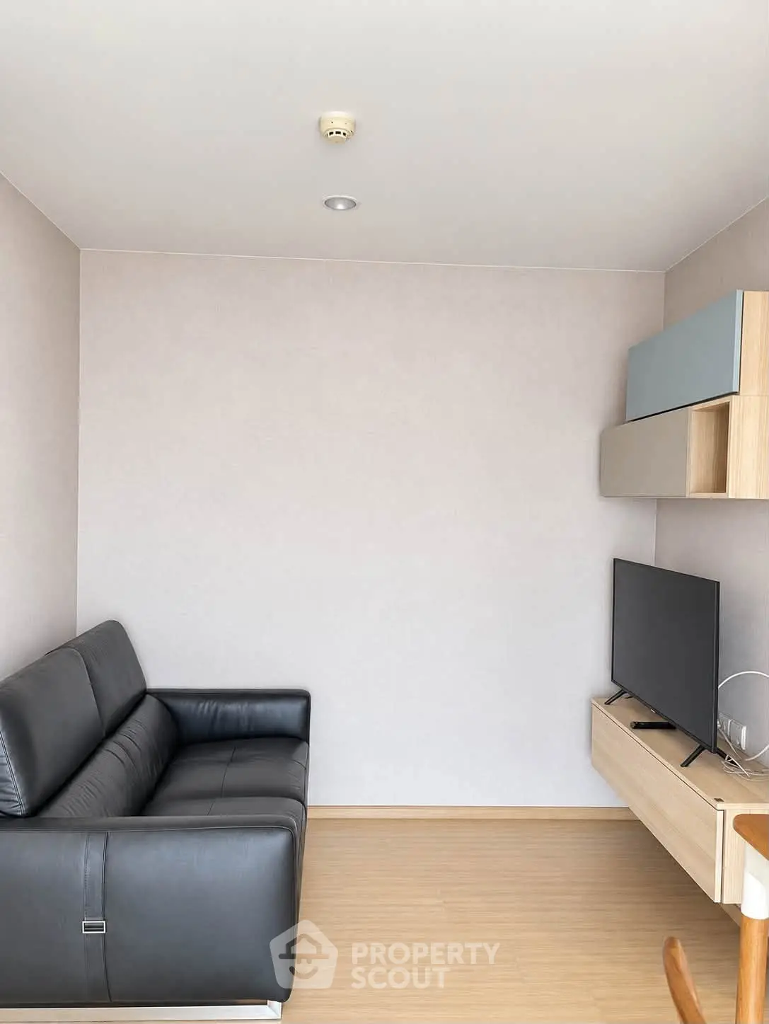 Modern minimalist living room with sleek black sofa and wall-mounted TV