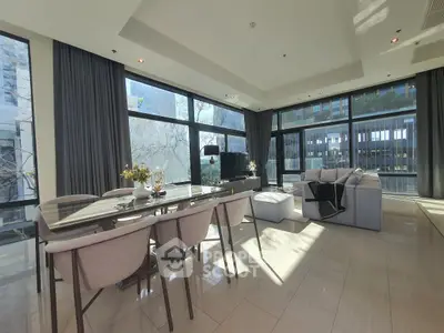 Spacious modern living room with large windows and elegant dining area, offering abundant natural light and stylish decor.