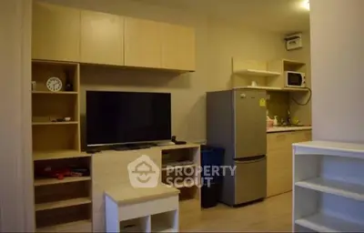 Modern apartment interior with sleek kitchen and entertainment area featuring TV and fridge.