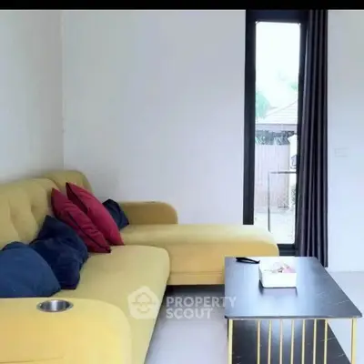 Stylish living room with modern yellow sofa and sleek coffee table near window.