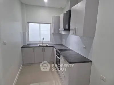 Modern kitchen with sleek cabinetry and built-in oven in a bright apartment.