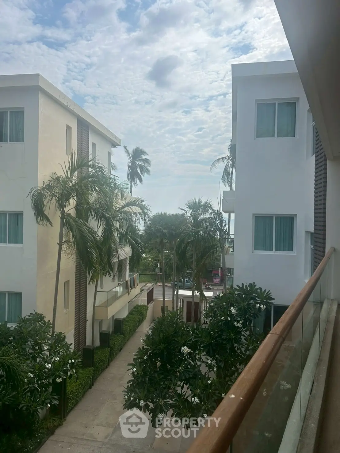 Modern apartment buildings with lush greenery and palm trees, offering a serene tropical view.
