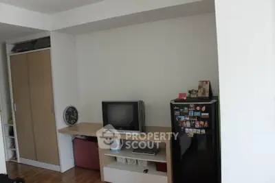 Cozy living room with TV, mini fridge, and storage space in modern apartment.