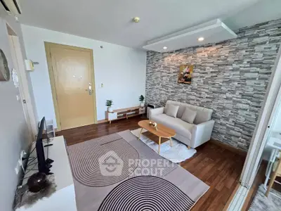 Modern living room with stylish decor and cozy seating area, featuring a textured accent wall and wooden flooring.