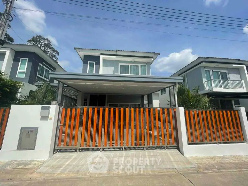 Modern two-story house with sleek design and vibrant orange fence in a suburban neighborhood.