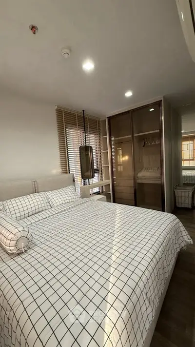 Cozy bedroom with modern design and ample natural light, featuring a stylish wardrobe and comfortable bedding.