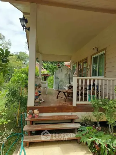 Charming wooden porch with lush greenery and cozy seating area, perfect for relaxation.