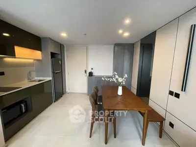 Modern kitchen with sleek design, featuring dining table and built-in appliances.