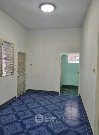 Spacious room with blue patterned tile flooring and white walls, ideal for versatile use.