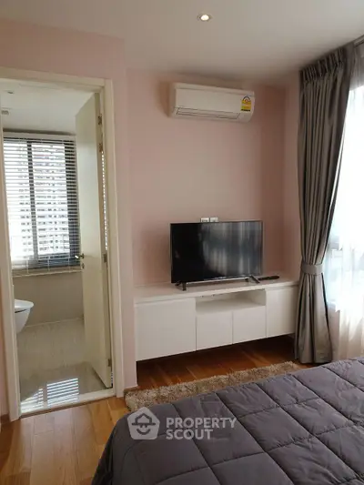Modern bedroom with TV, air conditioning, and ensuite bathroom in a stylish apartment.