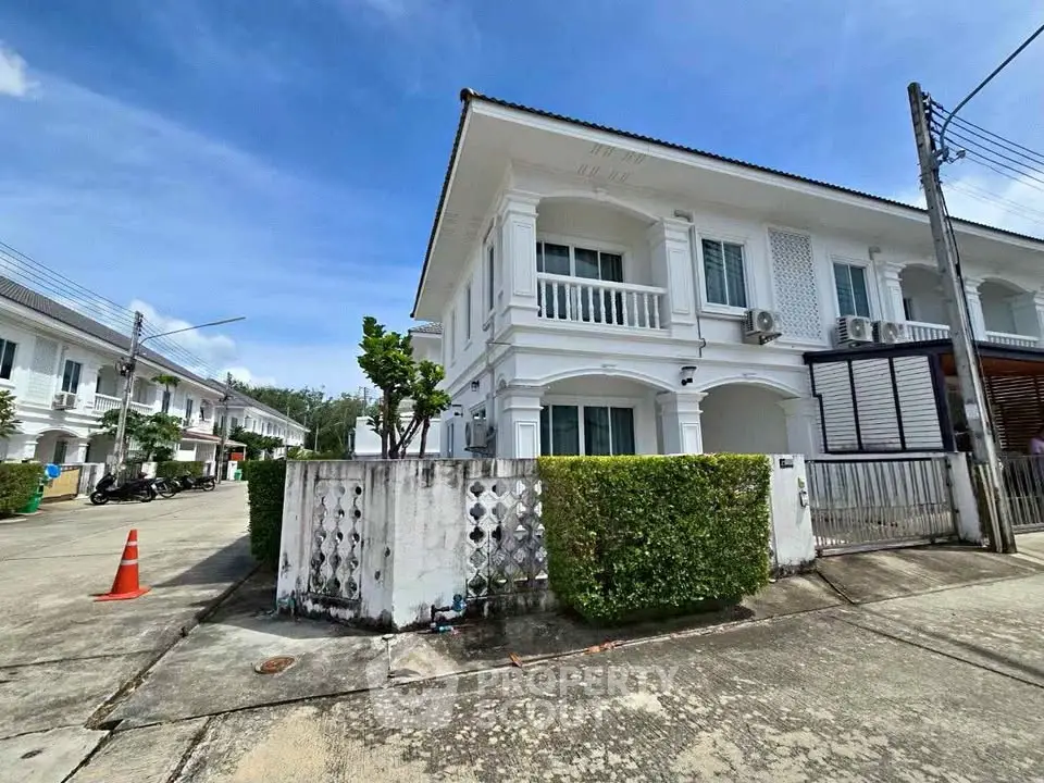Charming two-story white house with lush greenery and spacious driveway in a serene neighborhood.