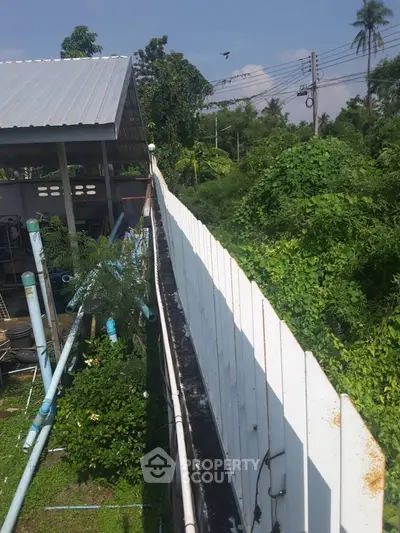Lush garden view with white fence and metal roof structure