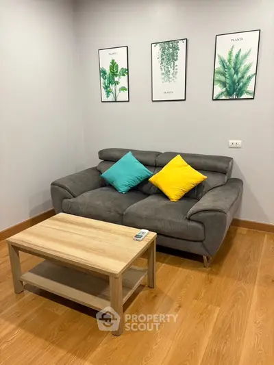 Cozy living room with modern sofa, vibrant cushions, and stylish plant artwork on the wall.