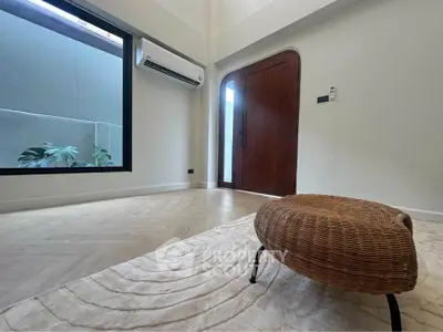 Spacious modern room with wicker ottoman and large window, featuring elegant wooden flooring and air conditioning.