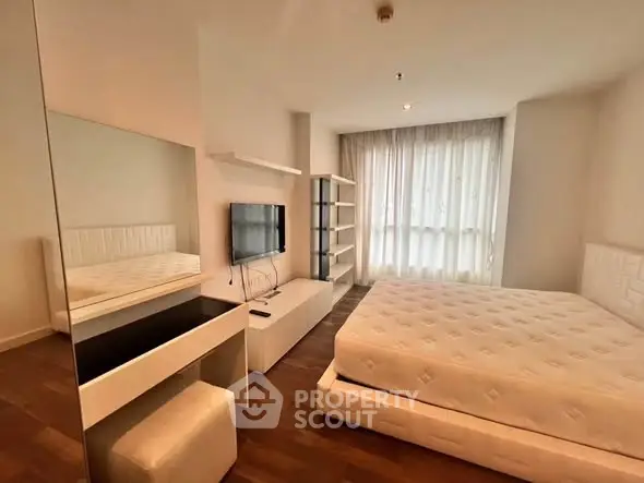 Modern bedroom with sleek furniture and large window for natural light.