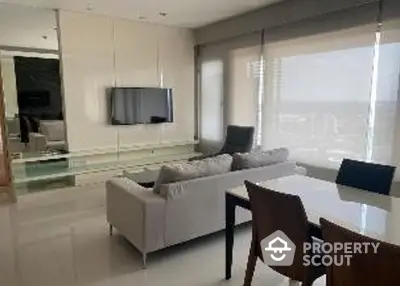 Modern living room with sleek furniture and large windows offering city views.