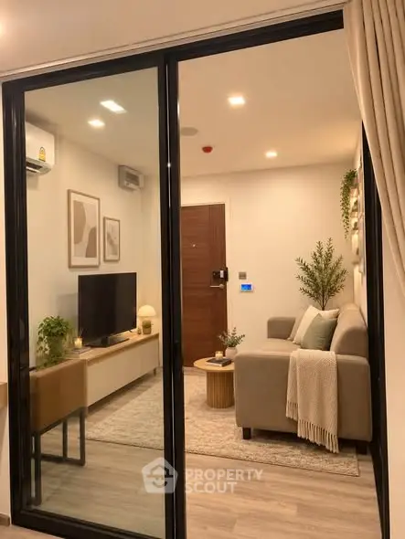 Modern living room with cozy sofa, stylish decor, and sleek glass door for a contemporary feel.