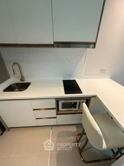 Modern compact kitchen with sleek white cabinetry and integrated appliances