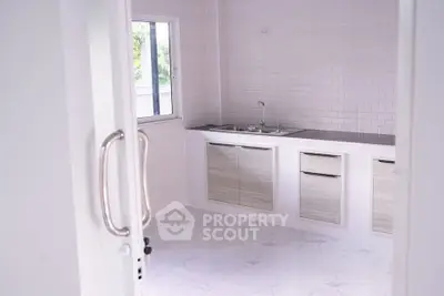 Modern minimalist kitchen with sleek cabinetry and large window