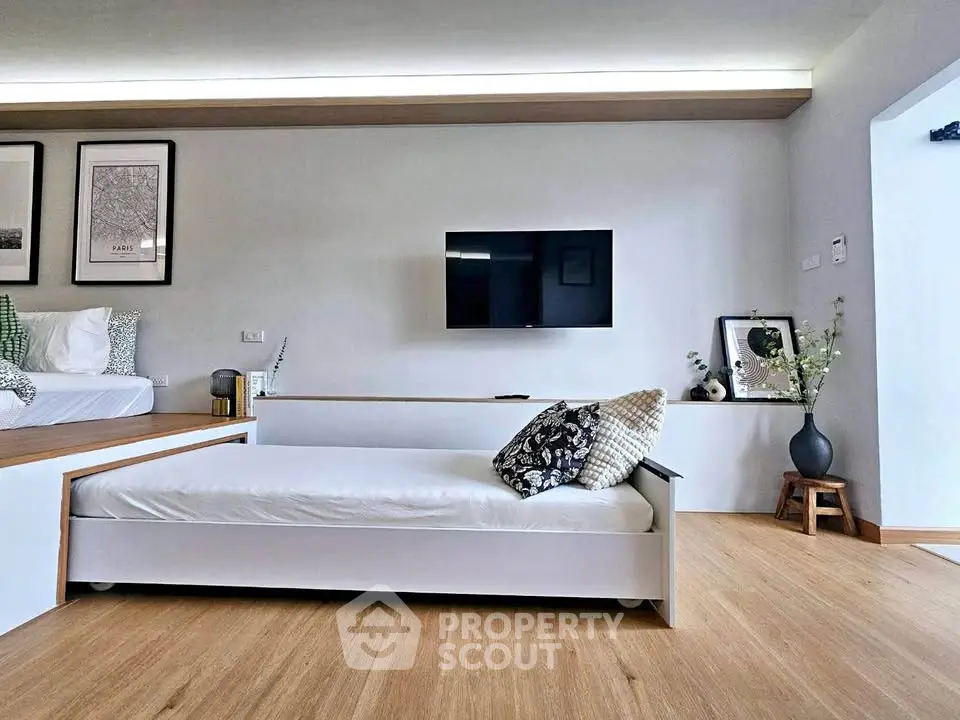 Modern living room with sleek furniture and wall-mounted TV, featuring minimalist decor and wooden flooring.