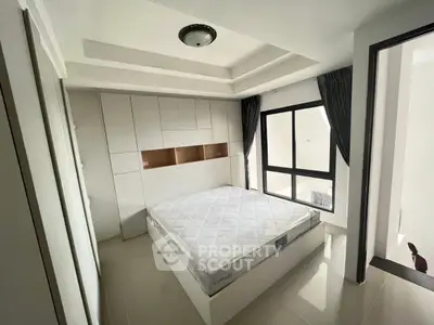 Modern bedroom with sleek design, featuring built-in storage and large window for natural light.