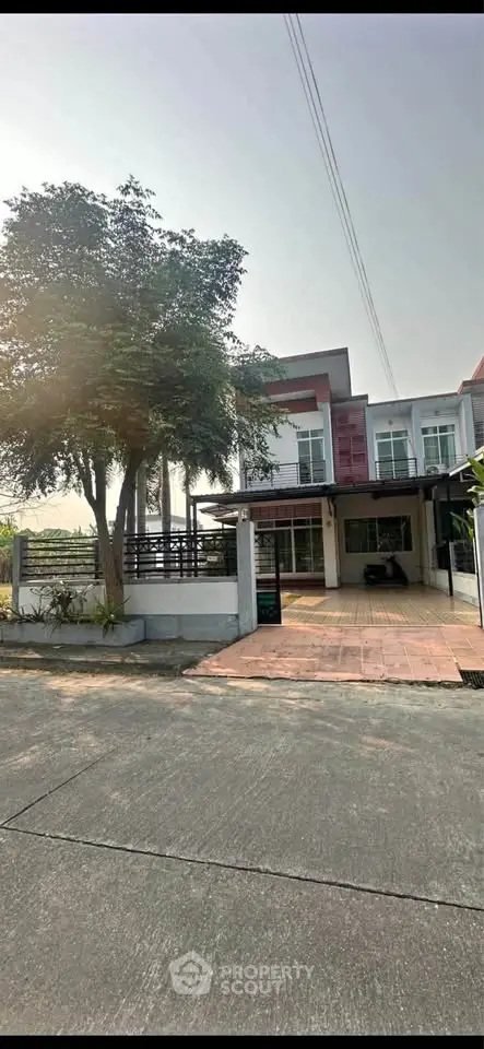 Modern two-story house with spacious driveway and lush greenery in a serene neighborhood.