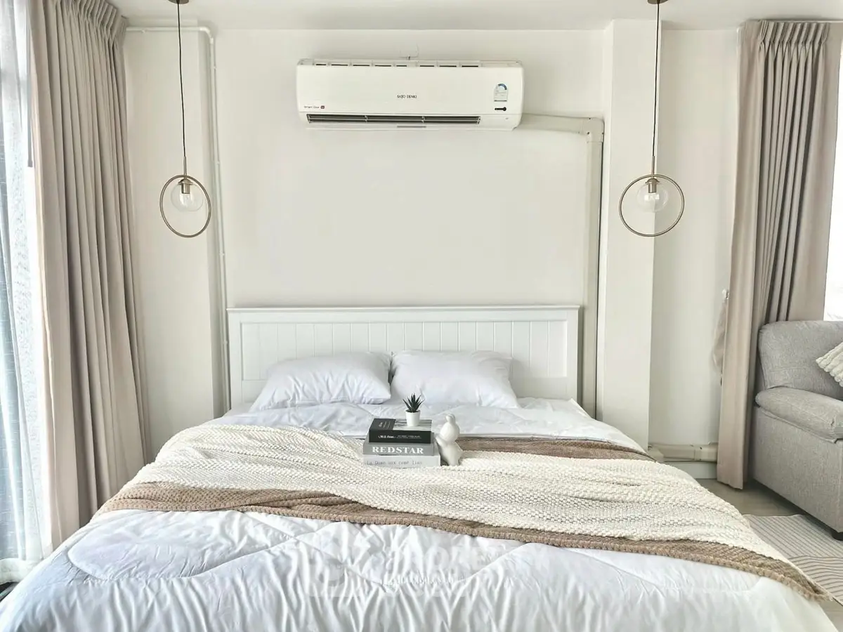 Modern bedroom with cozy bed, stylish lighting, and air conditioning in a bright, inviting space.