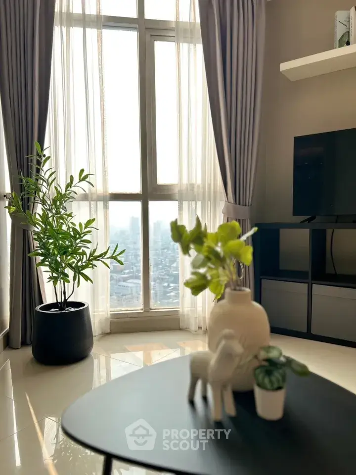 Bright living room with large window and modern decor, offering a stunning city view.