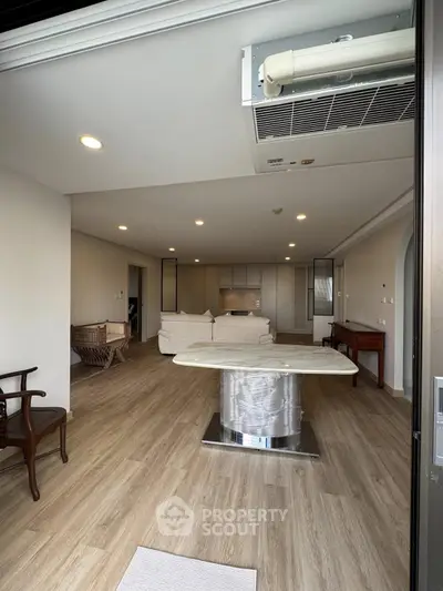 Spacious open-plan living room with modern furniture and elegant wooden flooring.