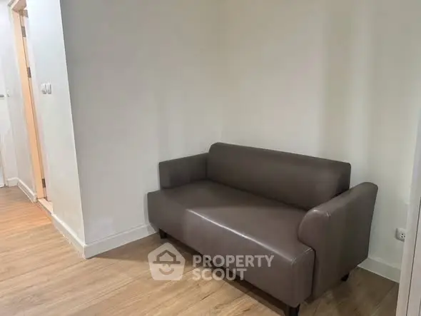 Cozy small sofa in a minimalist hallway with wooden flooring, perfect for compact living spaces.
