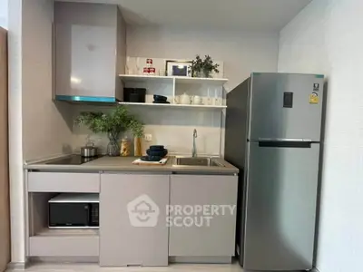 Modern compact kitchen with sleek cabinetry and stainless steel fridge