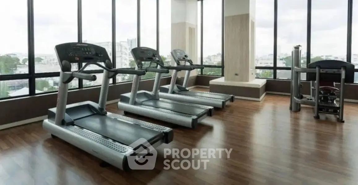 Spacious gym with modern treadmills and panoramic city views.