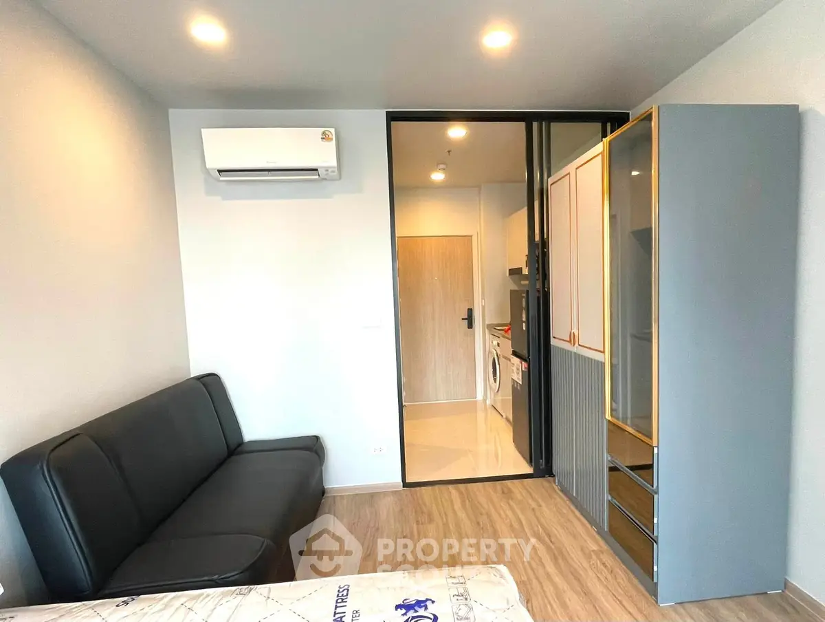 Modern studio apartment with sleek furniture and in-unit washer, perfect for urban living.