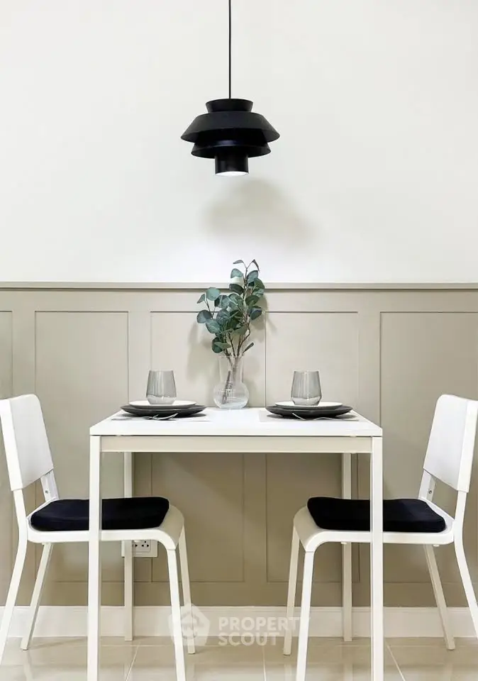 Modern dining area with sleek white table and chairs, stylish pendant light, and elegant wall paneling.