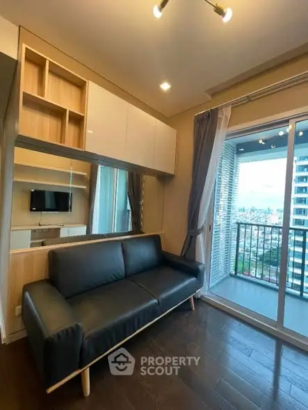 Modern living room with sleek black sofa and city view balcony.