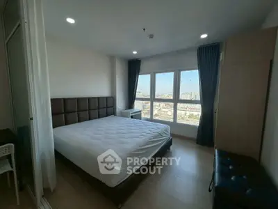 Spacious bedroom with large window offering stunning city view, modern furnishings, and ample natural light.