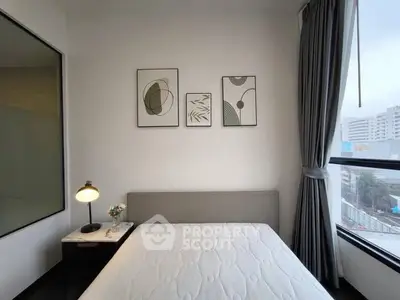 Modern bedroom with large window and stylish decor in urban apartment.