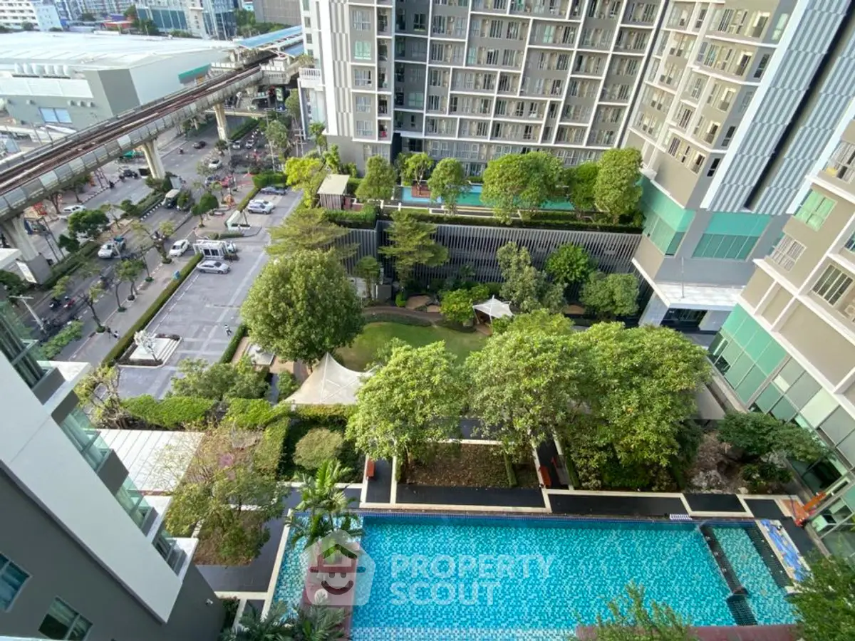 Stunning aerial view of modern condominium with lush garden and inviting swimming pool.