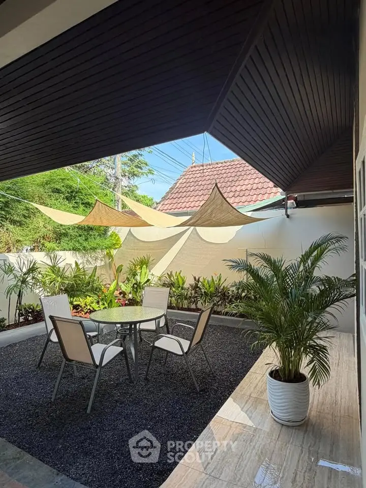 Charming outdoor patio with stylish furniture and lush greenery, perfect for relaxation and entertaining.